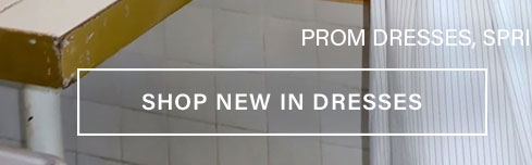 White banner "SHOP NEW IN DRESSES" over a blurred background of light fabric and green-tiled floor. Explore the latest fashion dresses.