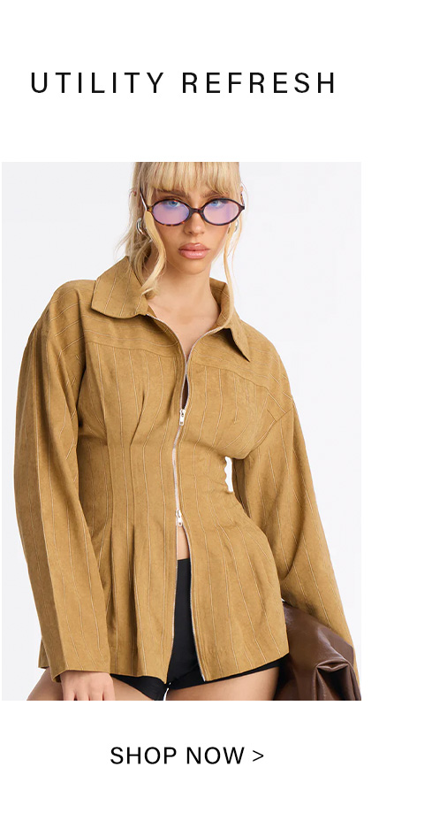Blonde woman wears a structured tan utility jacket with a silver zipper and vertical detailing, blue-tinted sunglasses. From the new Utility Refresh collection.