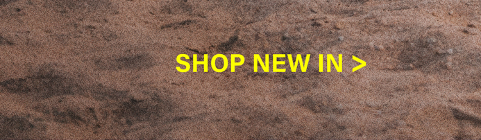 Yellow "SHOP NEW IN >" text on a textured brown sand background. Discover new arrivals and explore the latest collection.