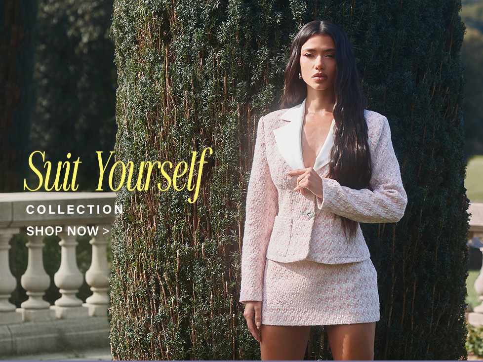 Stylish woman models a pink tweed blazer and mini skirt suit set against green foliage, promoting our new 'Suit Yourself' collection.