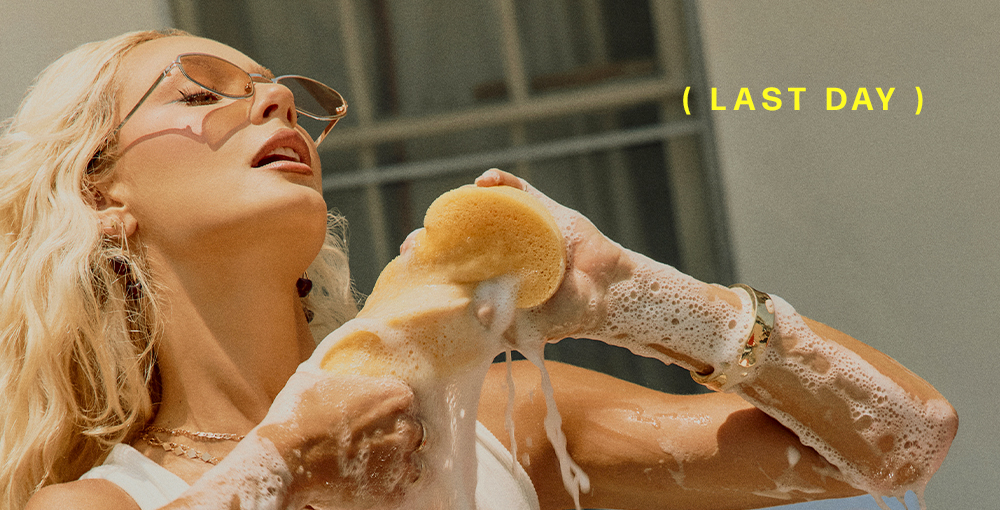 Blonde woman in sunglasses washing with a soapy sponge. LAST DAY promotion.