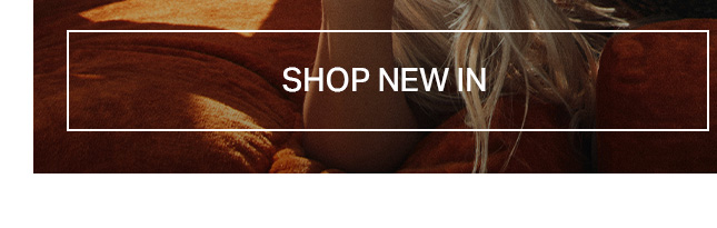 Close-up of a person with blonde hair on a warm brown textured surface, featuring a 'SHOP NEW IN' button for new arrivals and fashion.