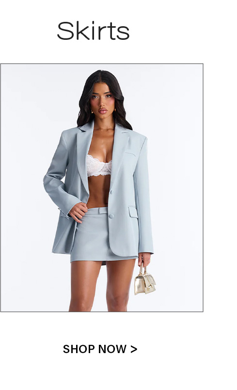 Model wears a light blue blazer, white lace bra, matching mini skirt, and holds a gold handbag. Shop the latest skirts collection.