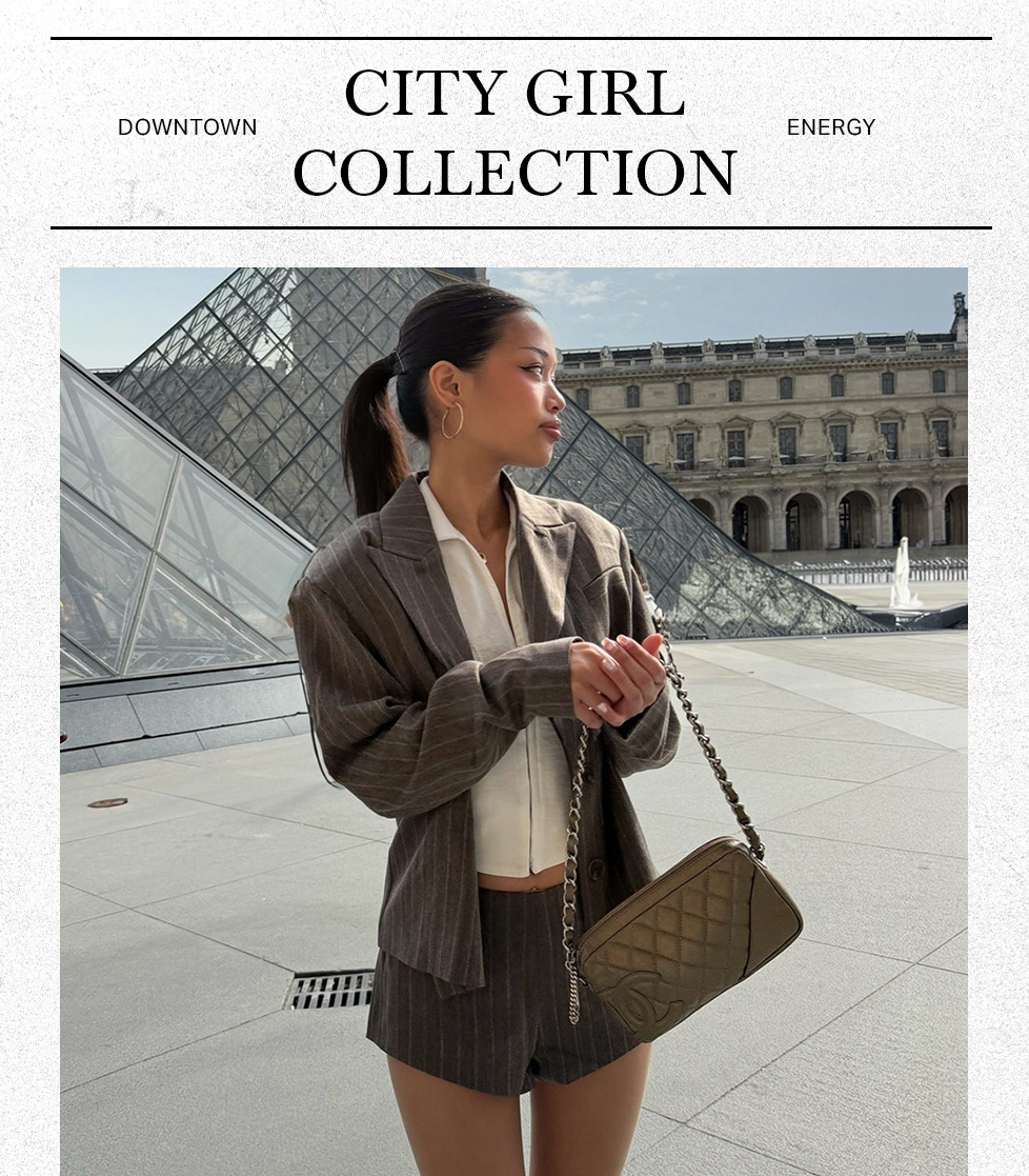 Woman in a brown pinstripe blazer set and quilted handbag poses in Paris, showcasing chic street style from the new City Girl Collection.