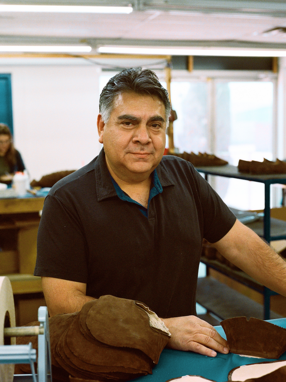 Man applying glue to shoe soles in a workshop.