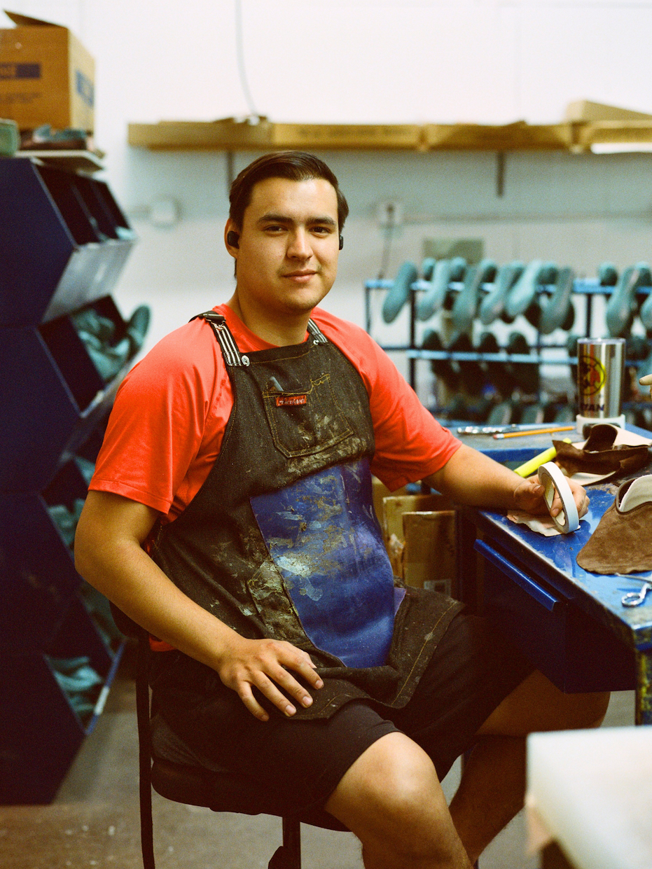 Man applying glue to shoe soles in a workshop.