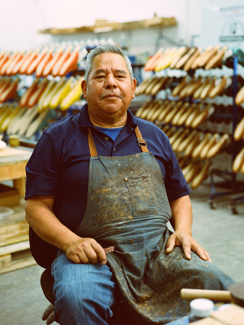 Man applying glue to shoe soles in a workshop.