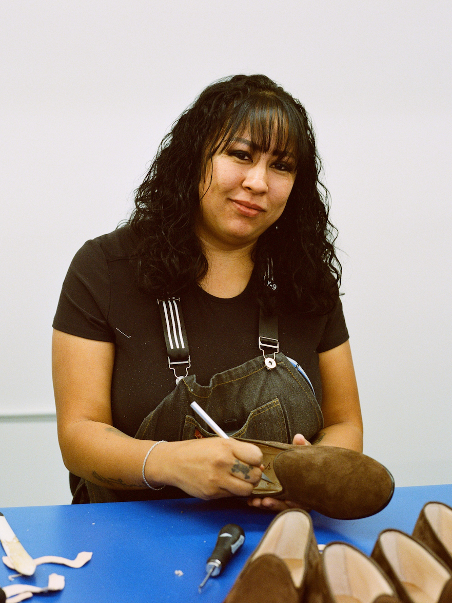 Man applying glue to shoe soles in a workshop.