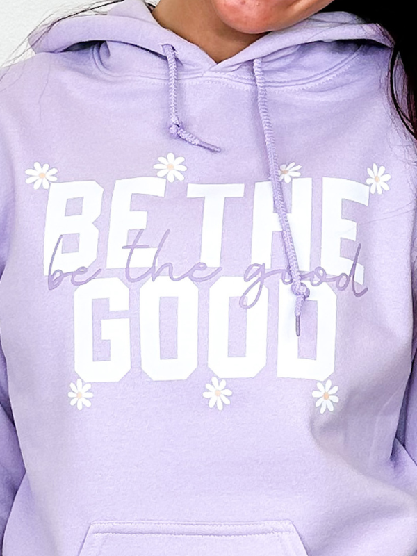 an image of a woman wearing a purple hoodie with the words be the good written on it