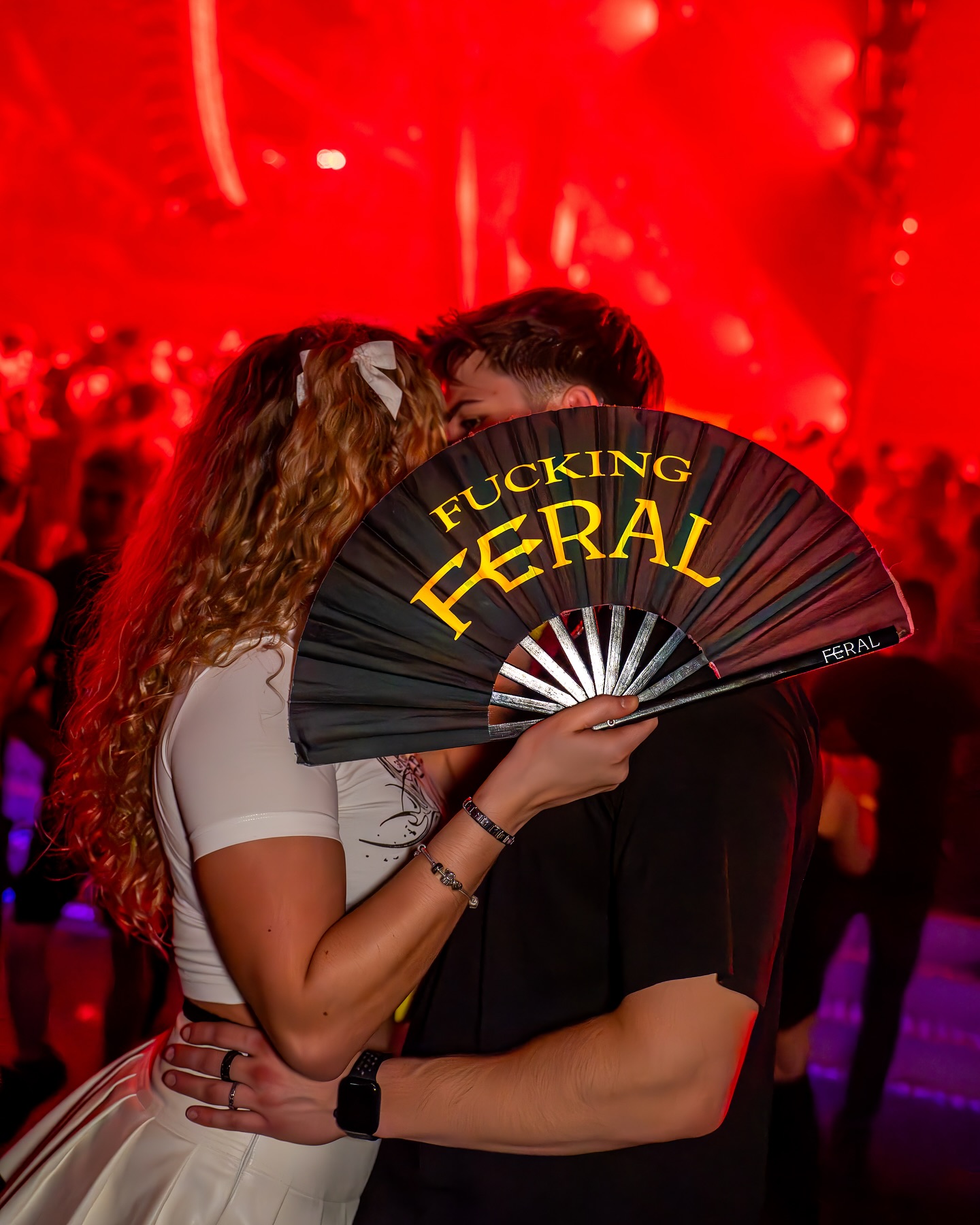 FUCKING FERAL fan — couple at a hard techno rave, red lighting, modern techno fashion