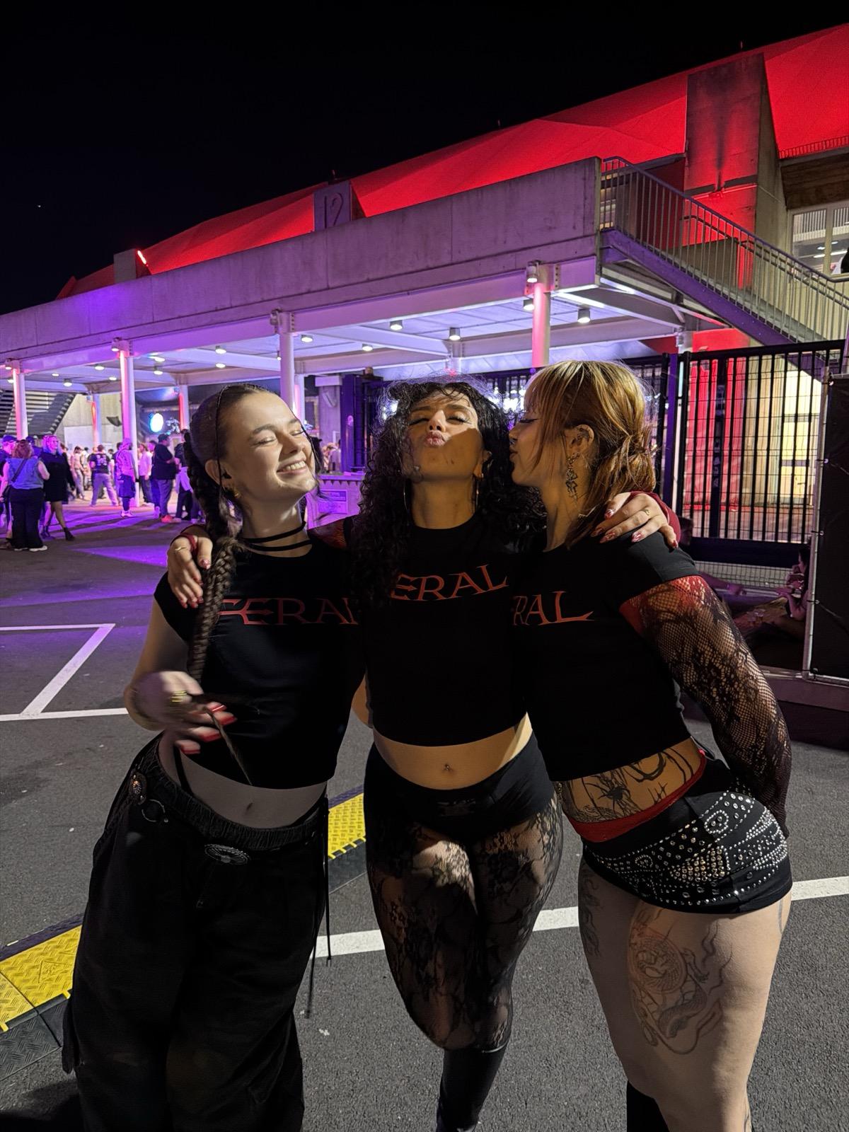 Three girls in FERAL baby tees, red lighting, rave scene — techno gift guide lifestyle