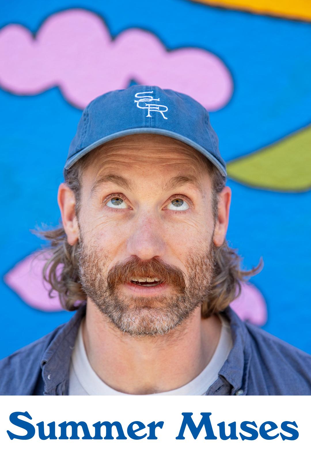 Close-up of a bearded man in a blue Stumptown cap looking up against a bright blue and pink mural. Headline reads, "Summer Muses".