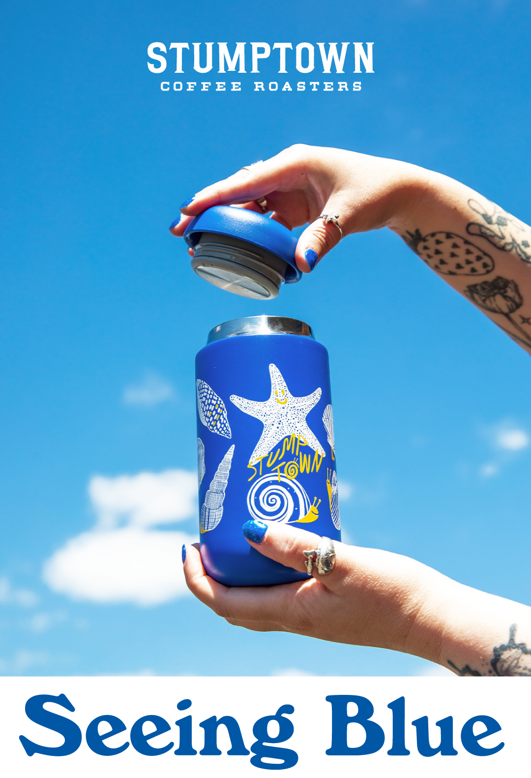 Hands holding blue Stumptown drinkware vessel with sea shell illustrations on it in front of a blue sky with clouds. Headline reads, "Seeing Blue".