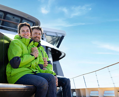 Couple sitting in their Atlas parkas aboard an Atlas yacht on the Water's Edge Observation Deck