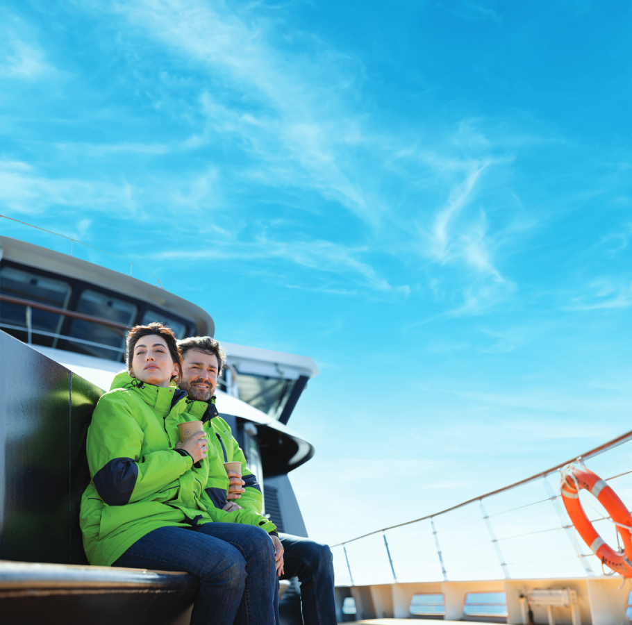 Couple sitting at Water's Edge observation deck aboard an Atlas yacht in their parkas