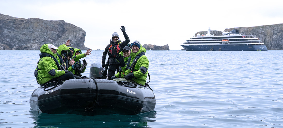 Atlas explorers on a Zodiac safari with their expedition leader with the yacht in the back