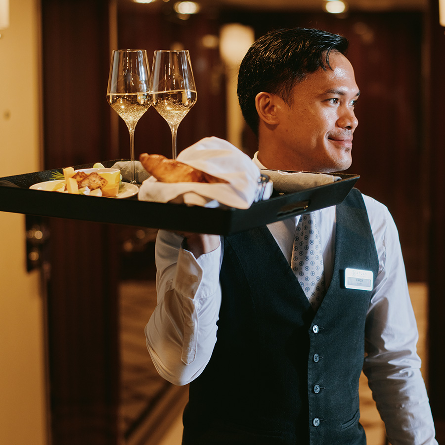 Butler carrying a tray of food and champagne glasses