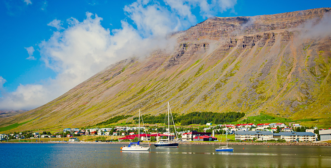 Houses and boats along a mountainside harbor in Ísafjörður, Iceland