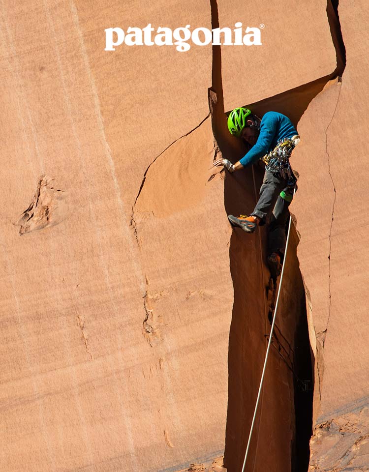A climber inches their way up a wide offwidth.