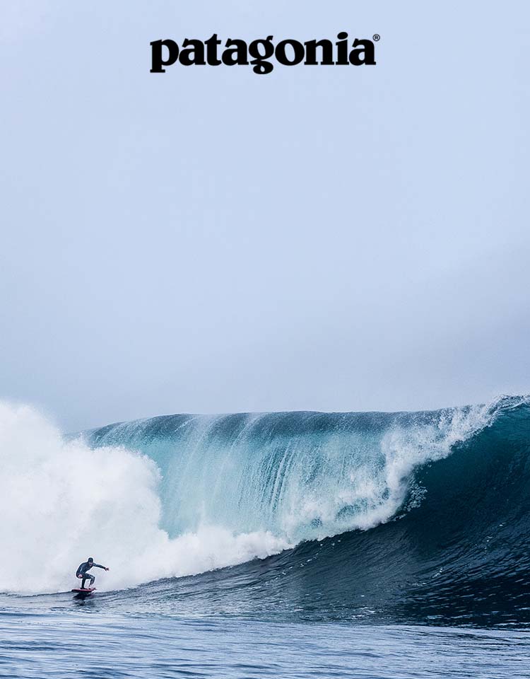 A surfer rides just in front of the breaking portion of big wave.