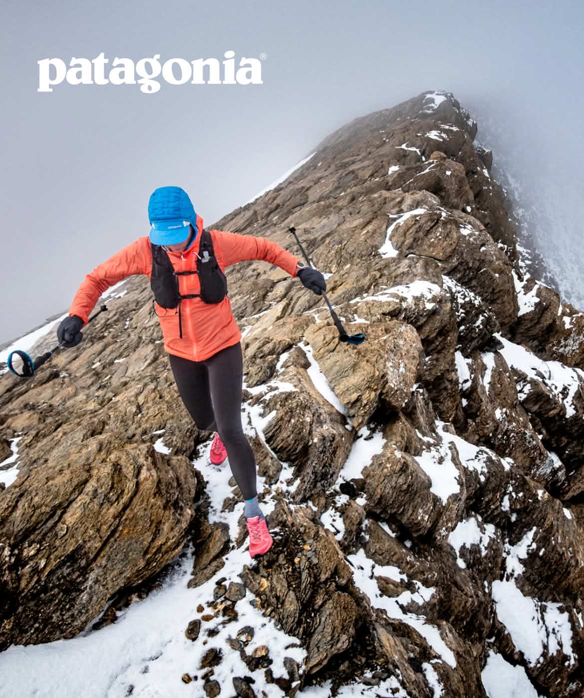A trail runner traverses a rocky ridge with scattered snow.  