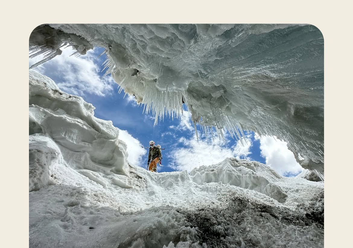 A mountaineer peers into a crevasse