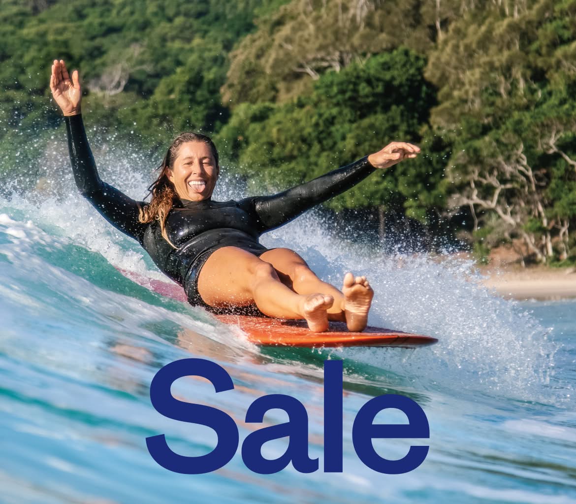 A person sits on a surfboard while riding a wave.