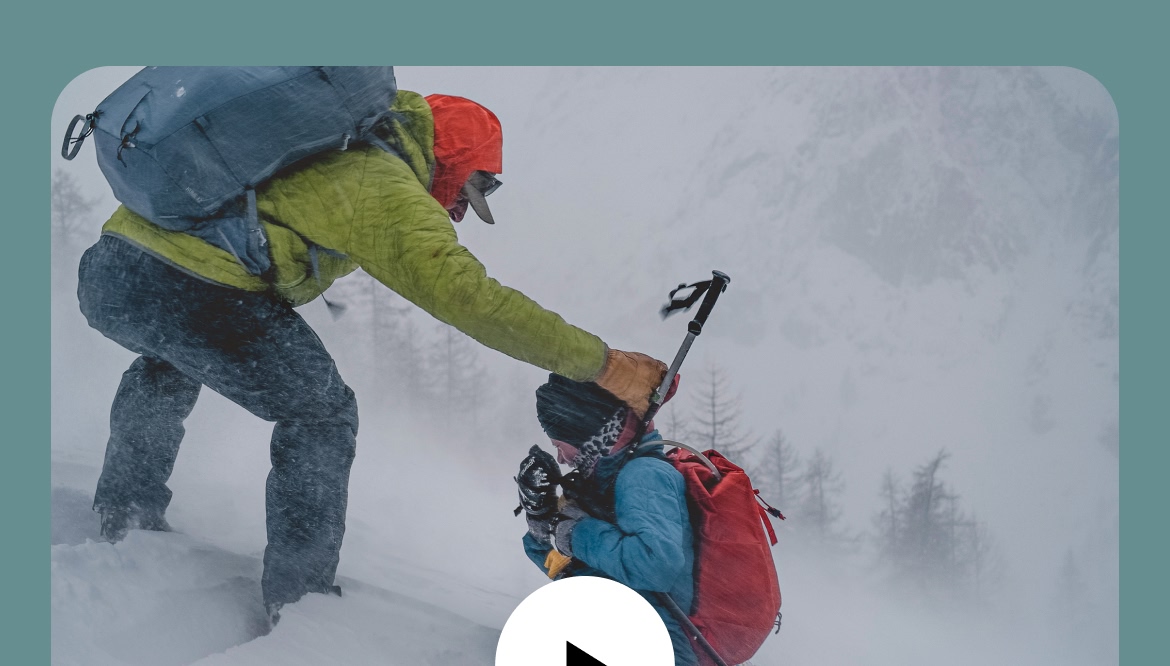 A grown-up helps a kid get their hood up during a blizzard.