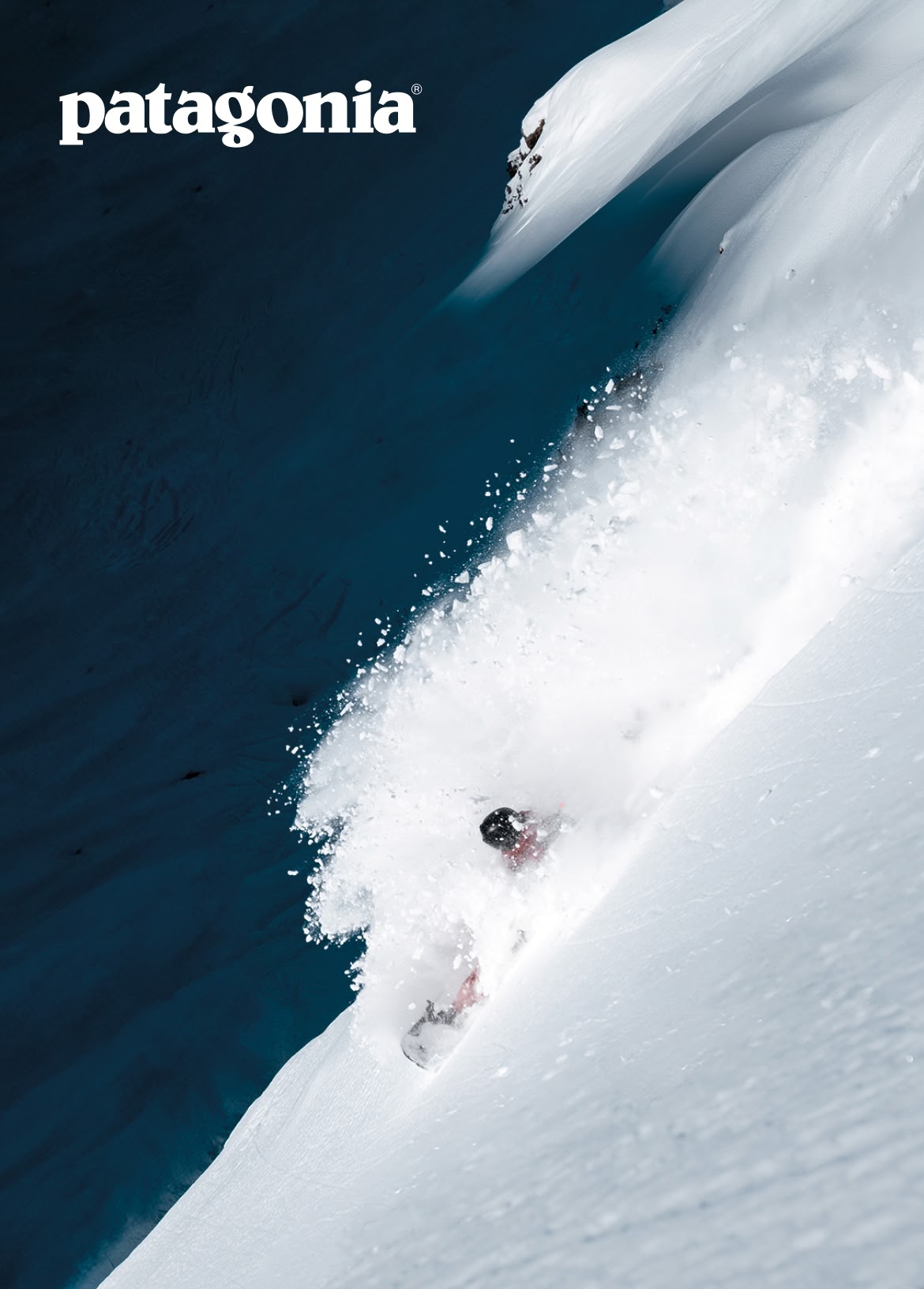 Patagonia. A snowboarder makes a big turn in deep powder.