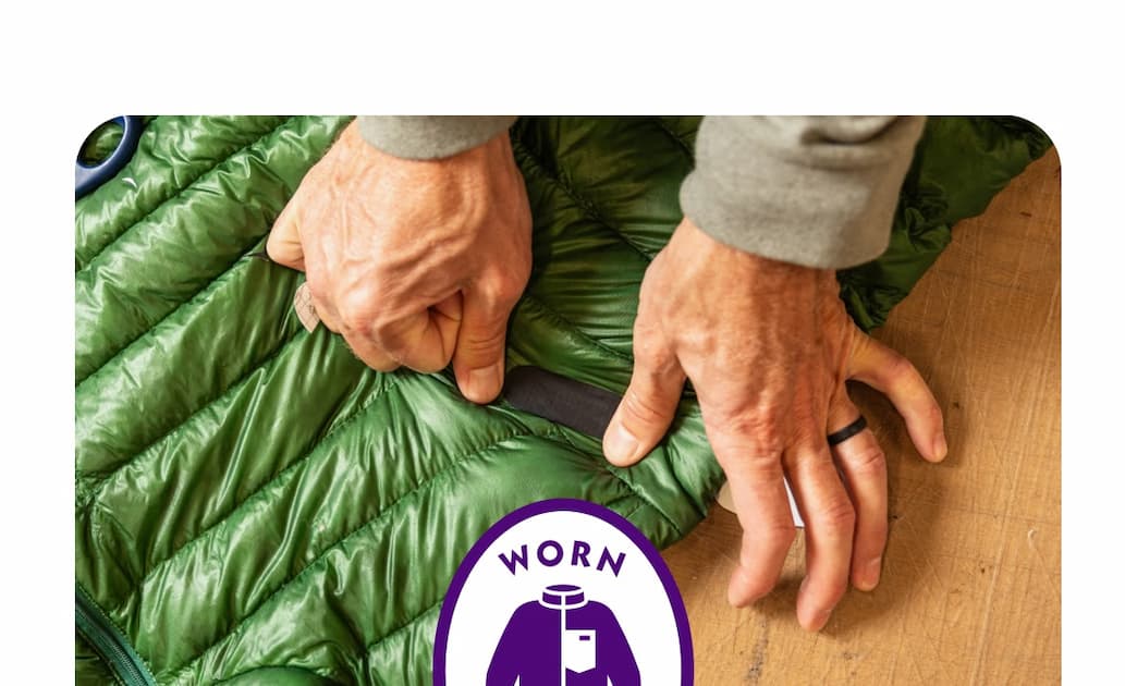 A person places a patch over a rip in a jacket.