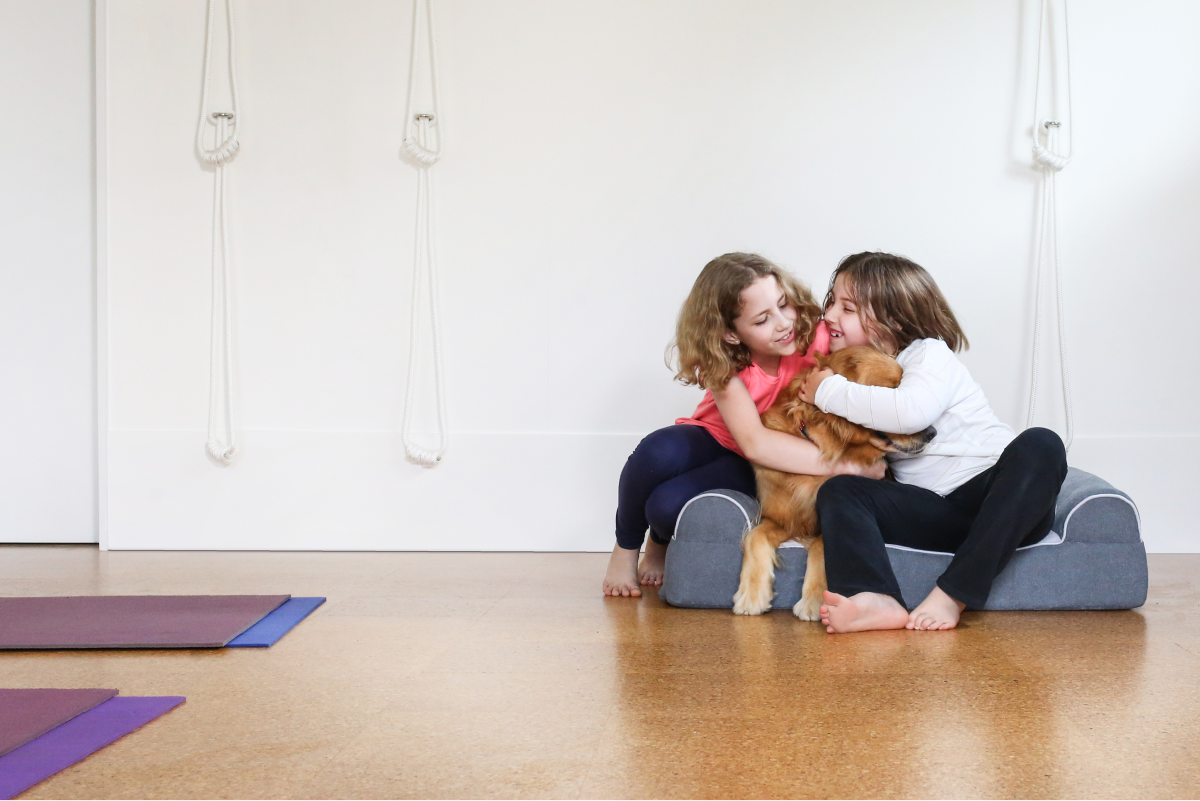 Two girls hugging their dog while using the Dog Cloud Bed