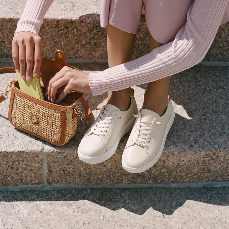 The Balance Cloud Sneaker in ivory, worn on stone steps with a raffia bag.