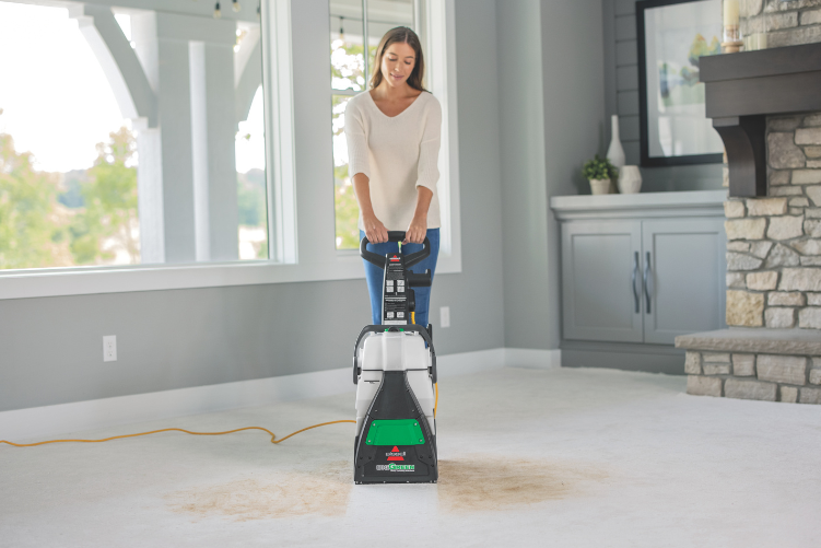 Woman cleaning carpet mess with a BISSELL Big Green