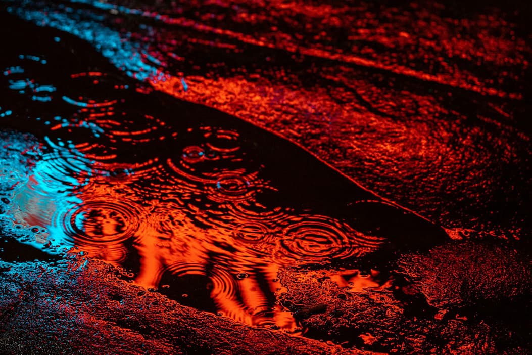 raindrop ripples in a neon-lit puddle. 