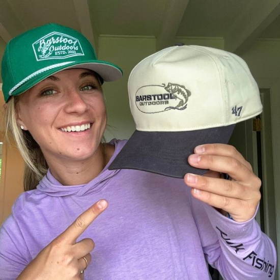 Sydney Wells posing with 2 Barstool Outdoors hats